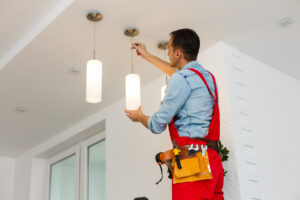 Electrician installing ceiling lamp